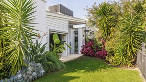 Une maison moderne dotée d’un jardin bien entretenu, comprenant diverses plantes et une pelouse.