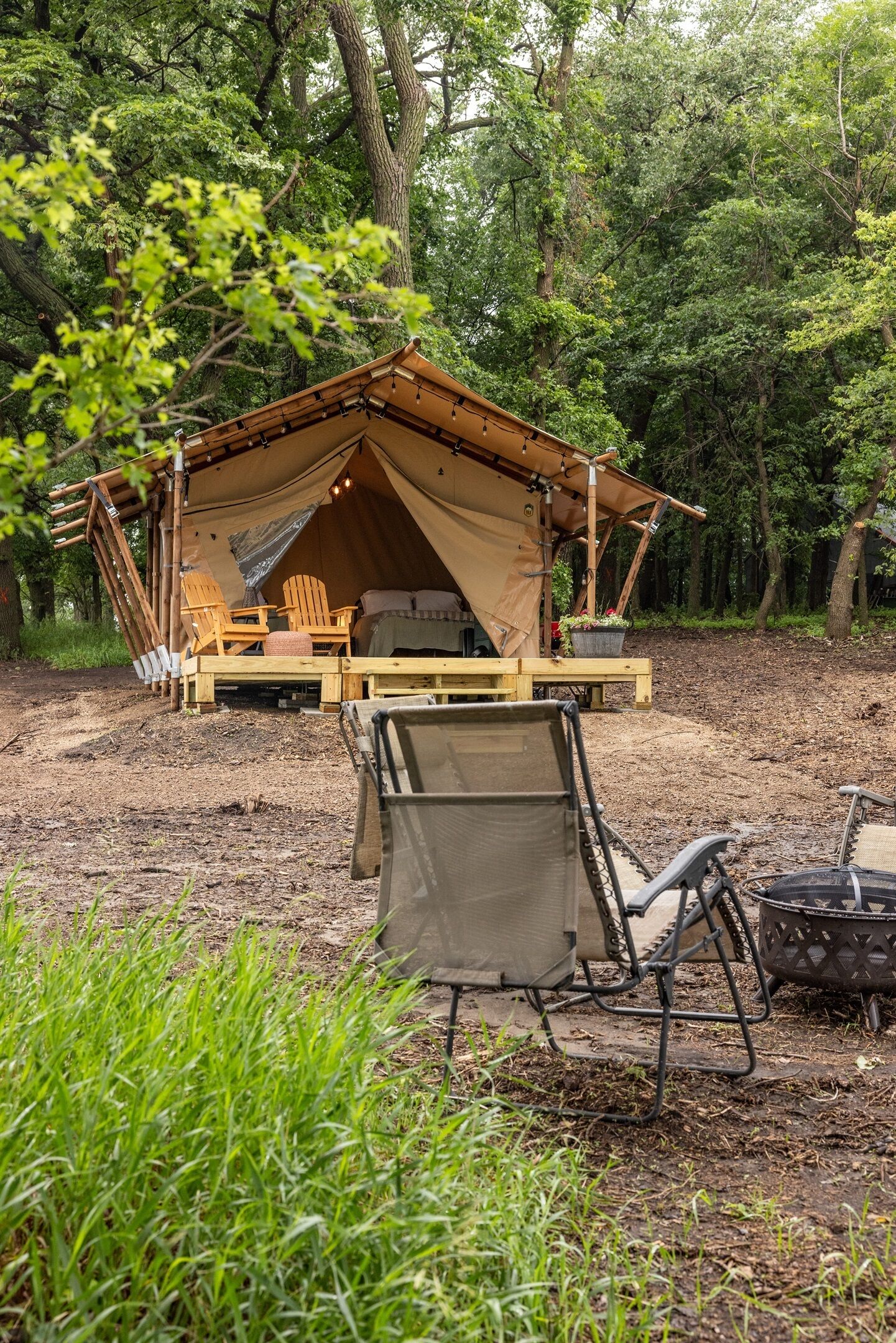 A tented accommodation with a bed, seating area, and a dining table.