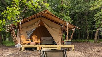 A tented accommodation with a bed, seating area, and a dining table.
