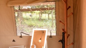 Une tente dotée d’une fenêtre, un support en bois avec une ampoule, un ventilateur et un extincteur.