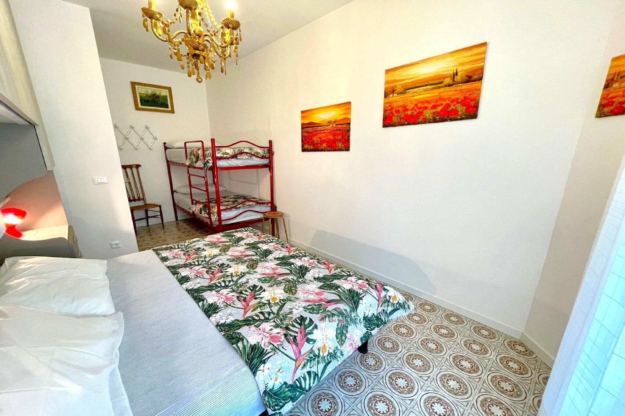 A bedroom with a bunk bed, a chandelier, and three paintings on the wall.