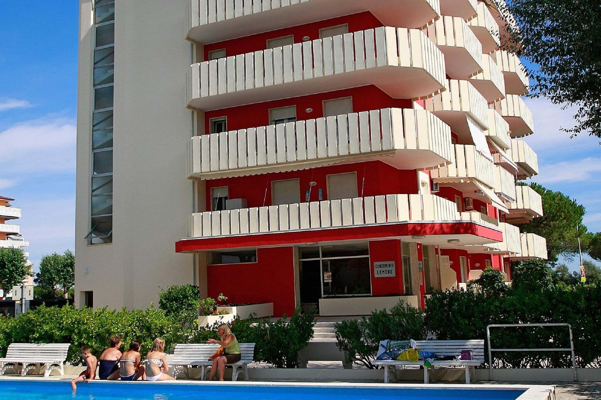 Un edificio a più piani con balconi, una piscina e un cartello che indica un ristorante.