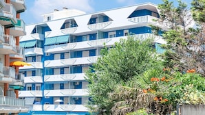 A multi-story hotel with balconies, a pool, and lush greenery. - Apartment a stone's throw from the beach (Porto Santa Margherita)