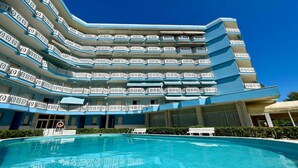 A multi-story hotel with a pool in the foreground.