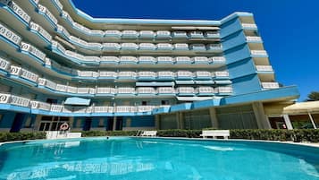 Ein mehrstöckiges Hotel mit Pool im Vordergrund.