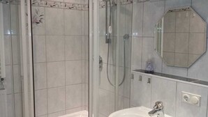 A bathroom with a glass-enclosed shower, a white sink, and a mirror. - Vacation apartment Alpenblume (Berchtesgaden)