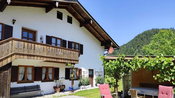 A two-story building with a balcony, outdoor seating, and a vineyard. - Vacation apartment Alpenblume (Berchtesgaden)