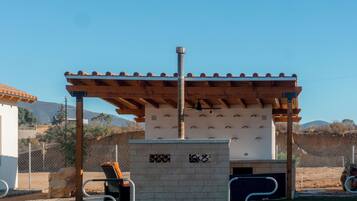 An outdoor patio area with a pergola, a barbecue grill, and a seating area.