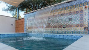Una piscina con fuente de agua y pared de azulejos.
