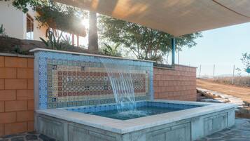 Ein Whirlpool mit einer gefliesten Wand und einem Wasserfall.