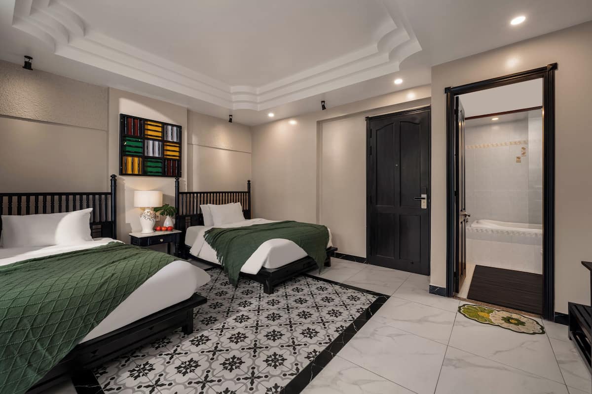 Ein Hotelzimmer mit zwei Betten, einem Badezimmer mit Badewanne und einer Dekowand.