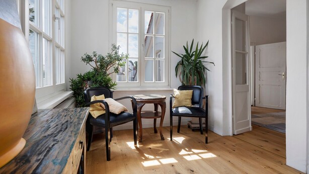 A room with a wooden floor, a round table, two chairs, a window with white shutters, and a potted plant. - Apartment 'Am Herforder Tor Für' with Private Garden, Balcony and Wi-Fi (Bad Salzuflen)