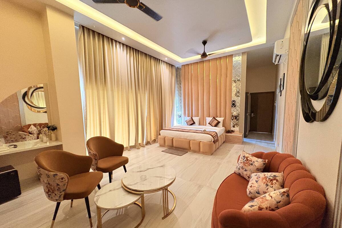 A modern hotel room with a bed, a sofa, a coffee table, and a chair.
