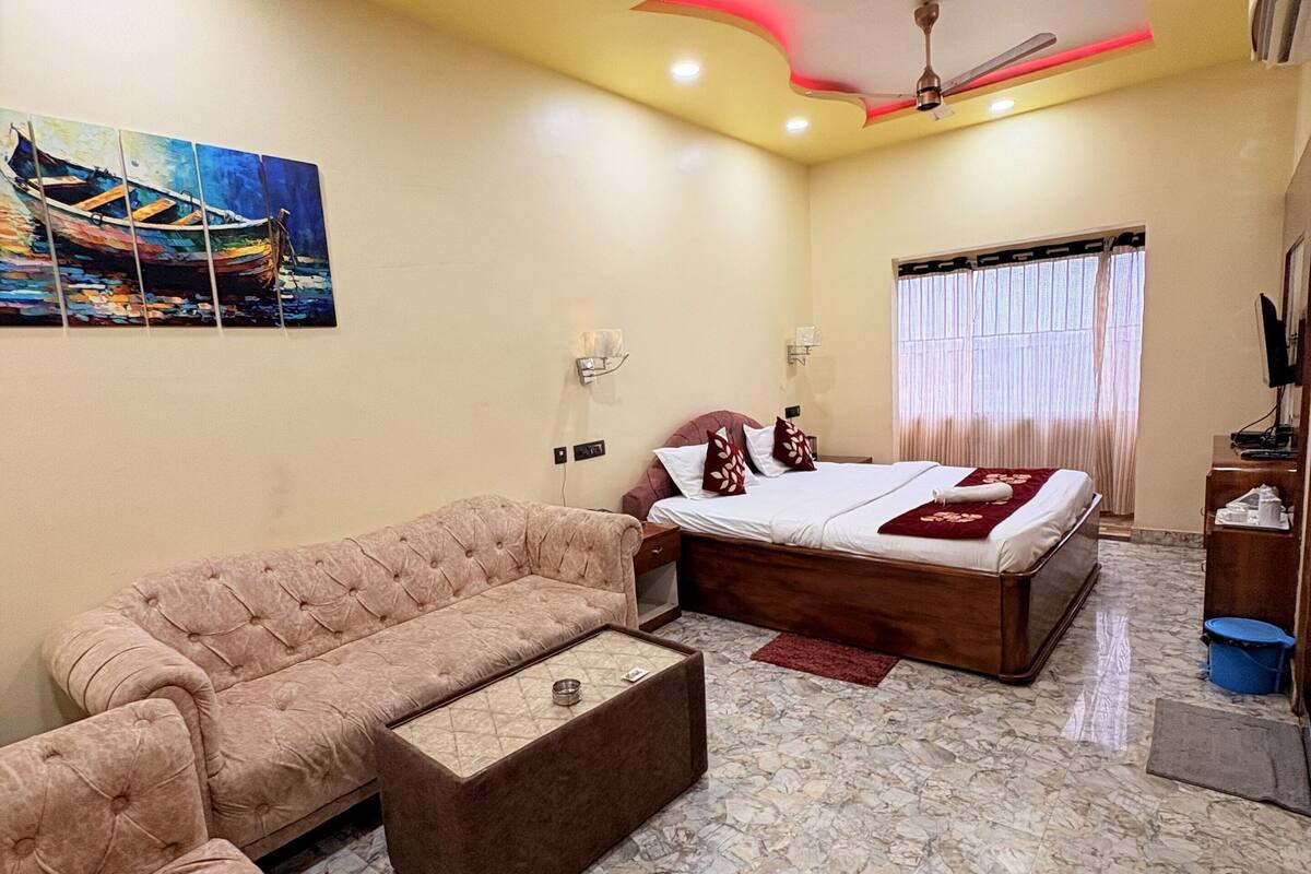 A bedroom with a bed, a sofa, a coffee table, and a ceiling fan.