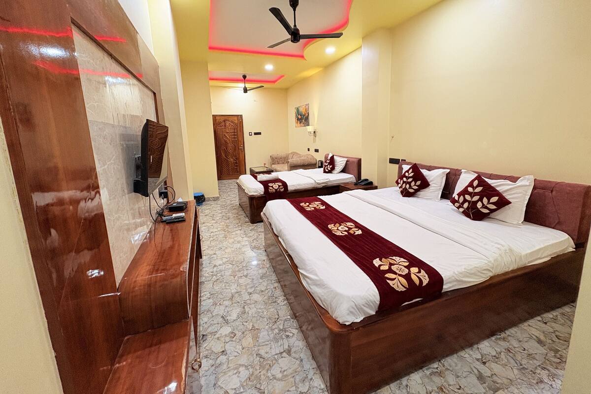 A hotel room with two beds, a wooden desk, a TV, and a ceiling fan.