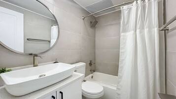 A modern bathroom with a white sink, toilet, and bathtub.