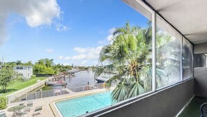 A balcony with a view of a swimming pool, palm trees, and a waterway. - Cordova Arms by Rocketstay (Fort Lauderdale)