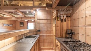 Une cuisine moderne avec des meubles en bois, une cuisinière à gaz, une machine à café et un meuble à vin.