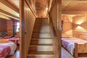 Un escalier en bois mène à une chambre aménagée en mezzanine, où se trouvent un lit et une petite table.