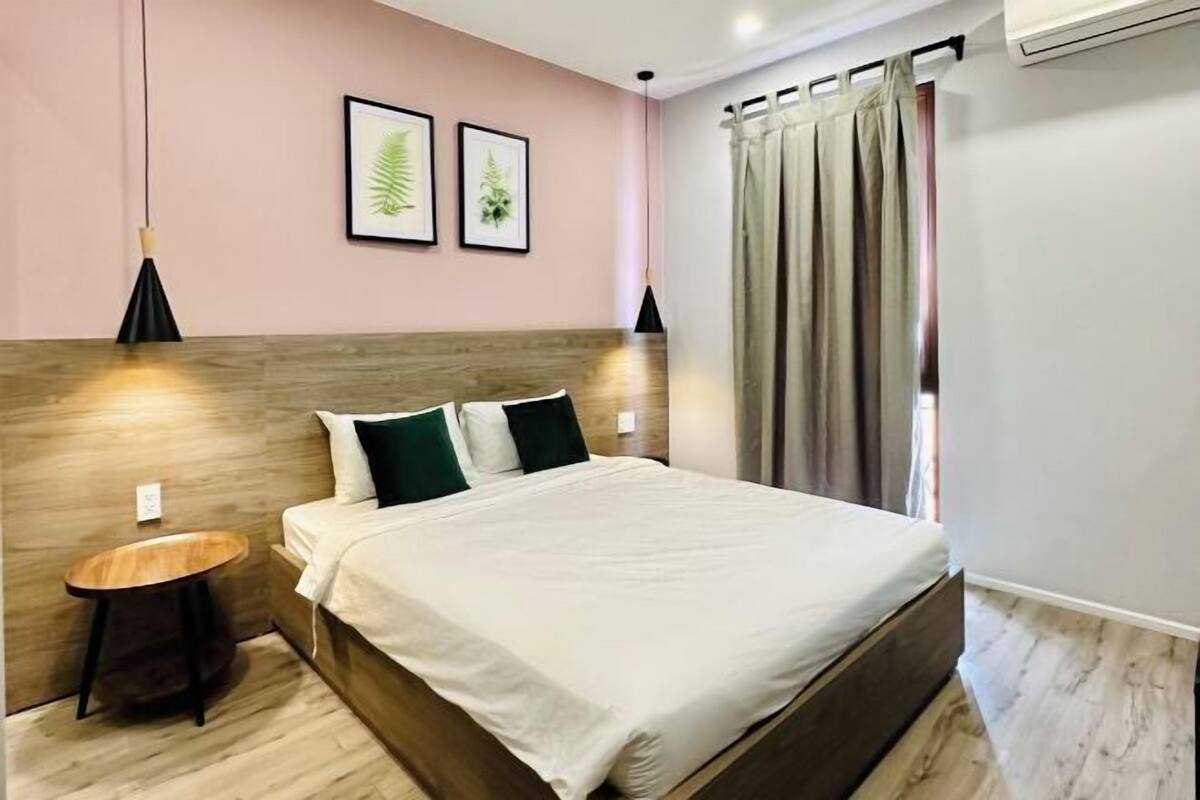 A neatly arranged bedroom with a bed, bedside tables, and framed botanical prints on the wall.