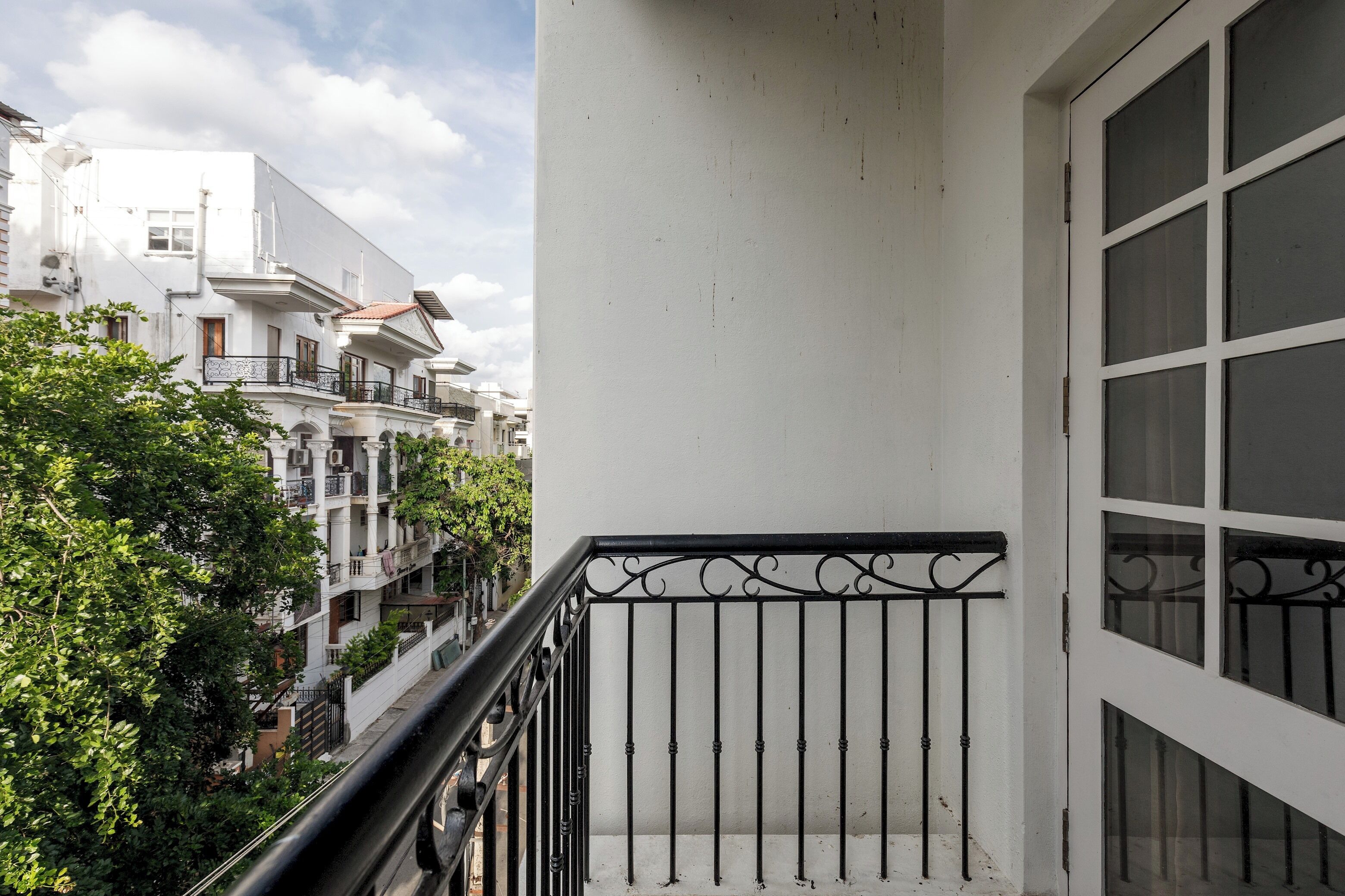 A balcony with a white wall and a black metal railing.