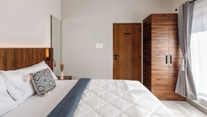 A bedroom with a bed, a wooden wardrobe, and a grey curtain. - The Monarch Stay by Red Olive (Bengaluru)