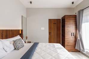 A bedroom with a bed, a wooden wardrobe, and a grey curtain. - The Monarch Stay by Red Olive (Bengaluru)