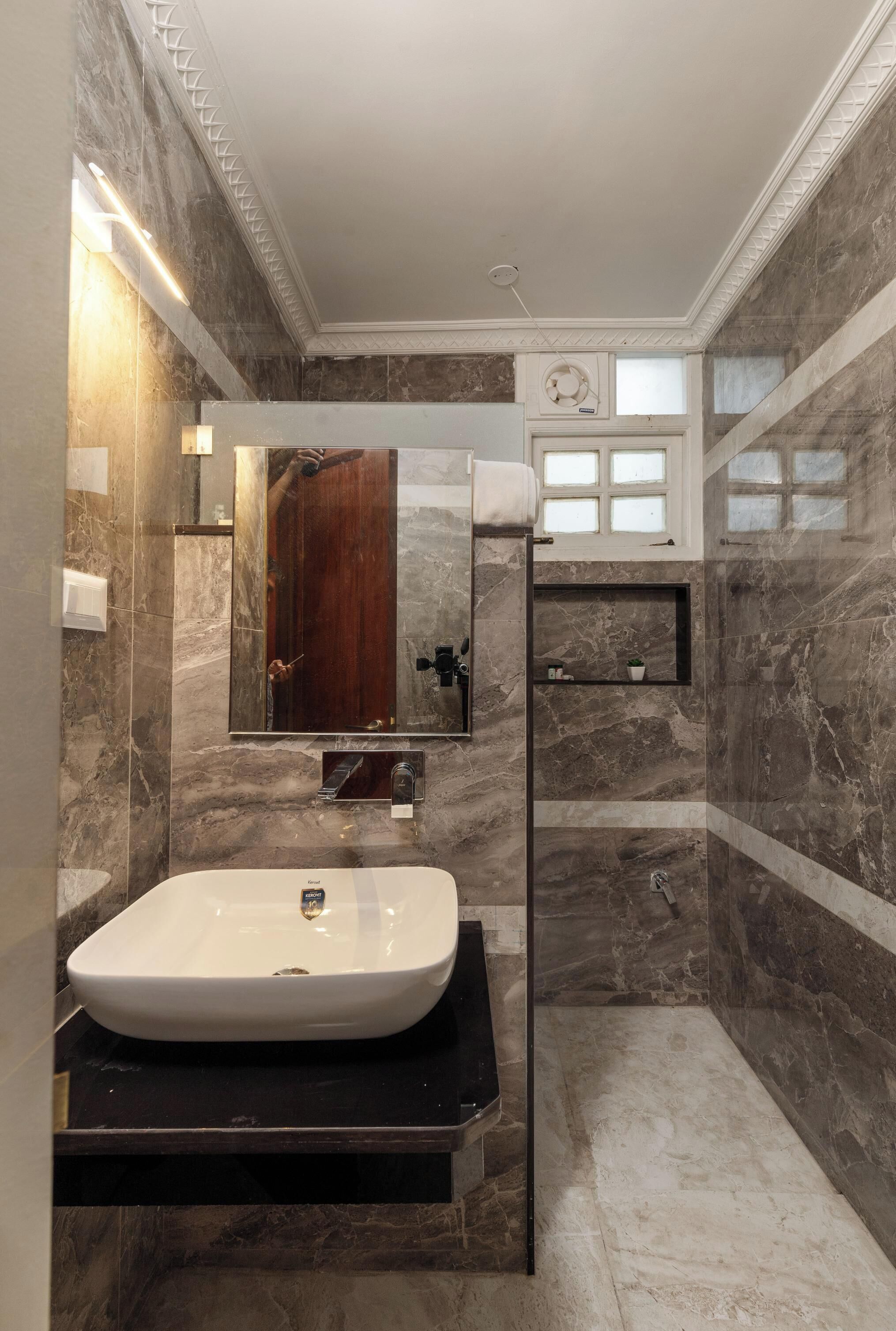 A modern bathroom with a large rectangular sink, a mirror, and a shower area.