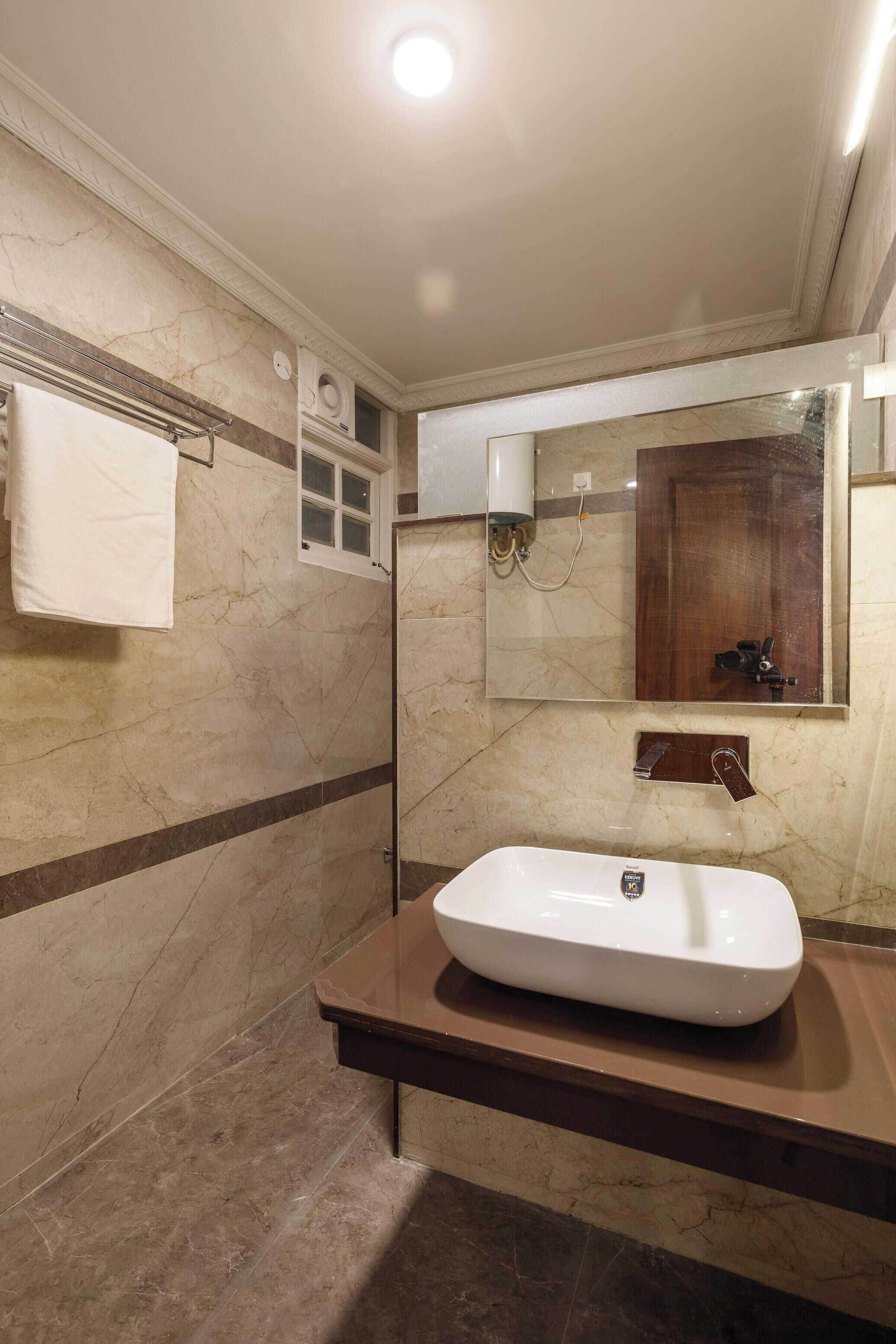 Un bagno con pavimento in marmo, un lavandino bianco, uno specchio e un portascopino.
