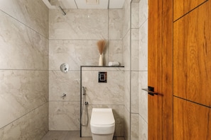 A bathroom with a toilet, shower, and wooden door.