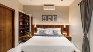 A modern bedroom with a large bed, wooden wardrobe, built-in shelves, and bedside tables with lamps. - Aurum Heights by Red Olive (Bengaluru)