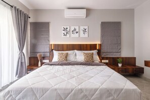 A modern bedroom with a large bed, wooden headboard, bedside tables, and a wall-mounted air conditioner. - Aurum Heights by Red Olive (Bengaluru)