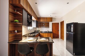 Una cucina moderna con mobili in legno, un frigorifero nero e un'area pranzo con due sedie.