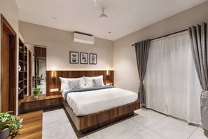 A modern bedroom with a wooden bed frame, a built-in wardrobe, and a large window with curtains. - Aurum Heights by Red Olive (Bengaluru)