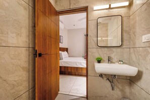 A modern bathroom with a wooden door, a white sink, and a mirror. - Aurum Heights by Red Olive (Bengaluru)