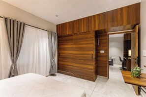 Camera moderna con un letto grande, un'armadiatura in legno e una scrivania con una pianta.