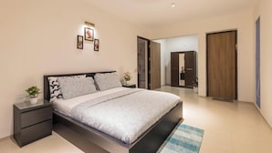 A modern bedroom with a bed, bedside tables, a nightstand, and a ceiling fan. - Golfer's Arena by Stayjade (Hosur)