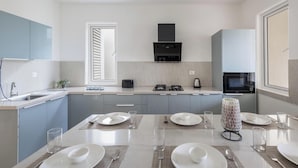 A modern kitchen with a central island, built-in appliances, and a window with blinds. - Golfer's Arena by Stayjade (Hosur)