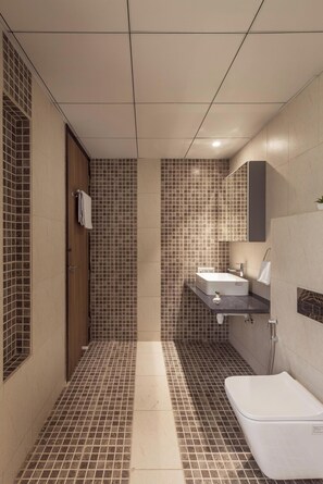 Un baño moderno con piso de baldosas, una puerta de madera, una bañera blanca y un lavamanos con un espejo arriba.