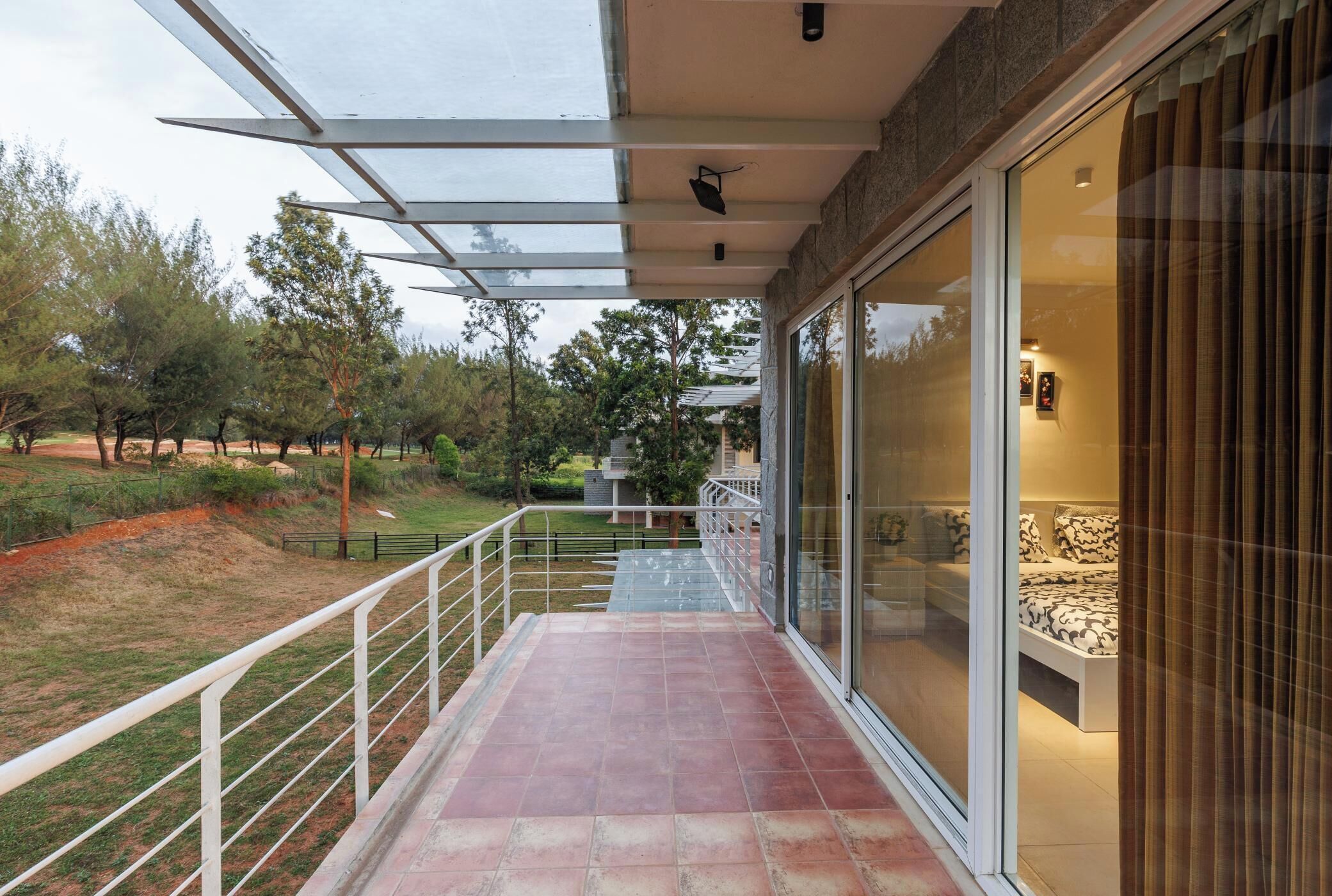 A balcony with a glass door leading to a bedroom.