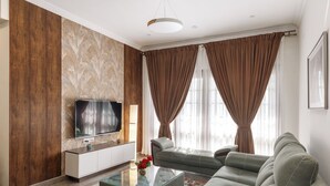 A modern living room with a flat-screen TV, a sofa, a coffee table, and a patterned wall. - Emerald Apartments by Red Olive (Bengaluru)
