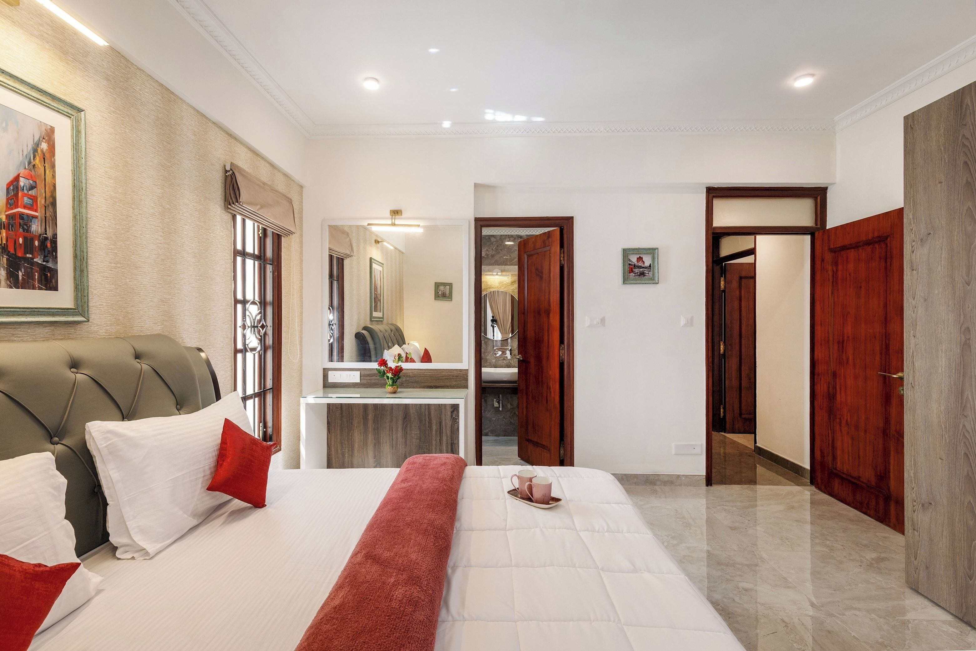 A hotel room with a bed, a bedside table, a mirror, and a door leading to another room.