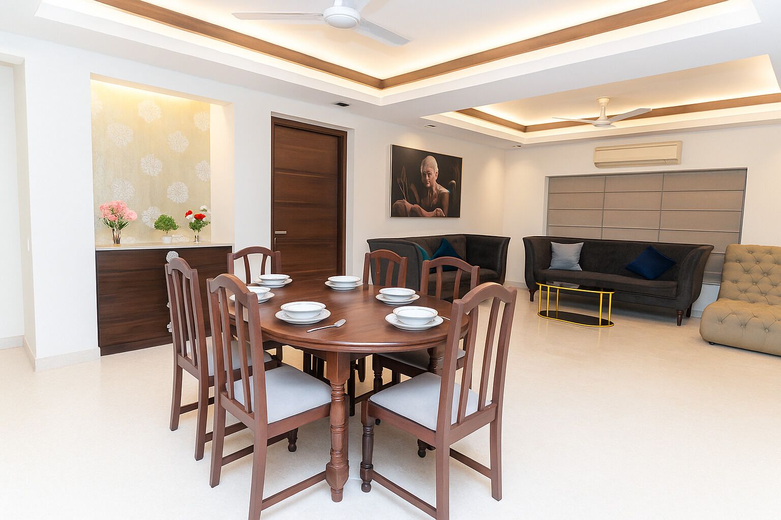 A modern dining area with a round wooden table, six chairs, and a ceiling fan.