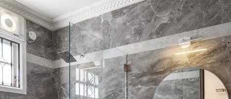 A modern bathroom with a glass-enclosed shower, a round mirror, and a vessel sink.