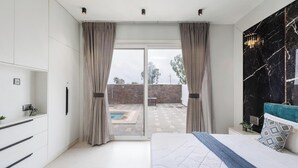 Un dormitorio moderno con una cama grande, una pared de acento de mármol y vistas a una piscina y un muro de ladrillo.