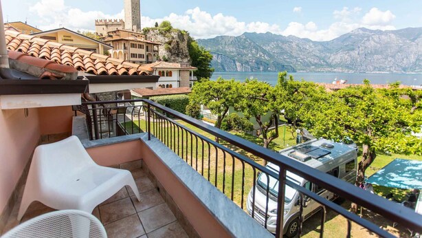 A balcony with a view of a lake, a castle, and mountains. - Villaggio Turistico Priori Malcesine (Malcesine)