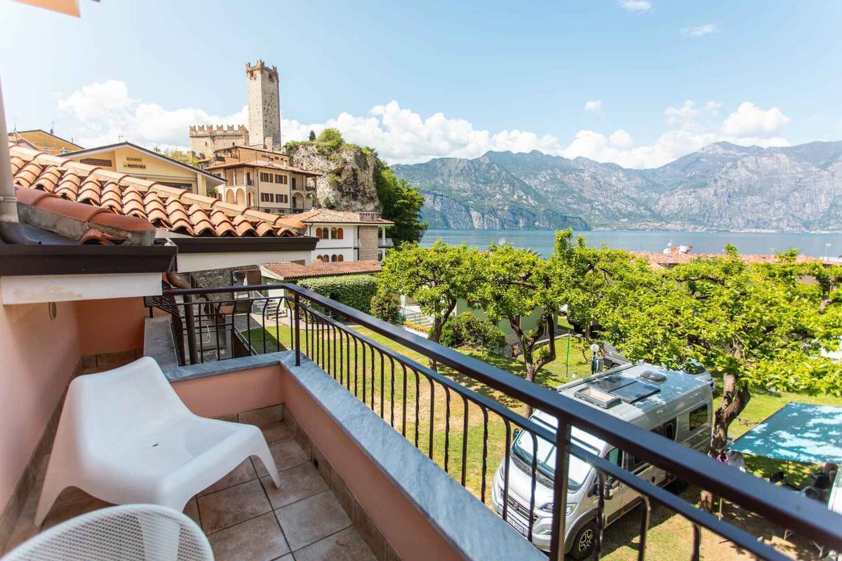 Uma varanda com vista para um lago, um castelo e montanhas.