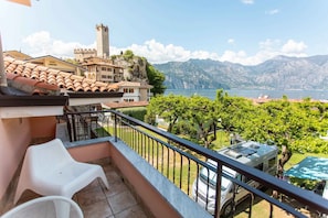 Un balcon avec vue sur un lac, un château et des montagnes.
