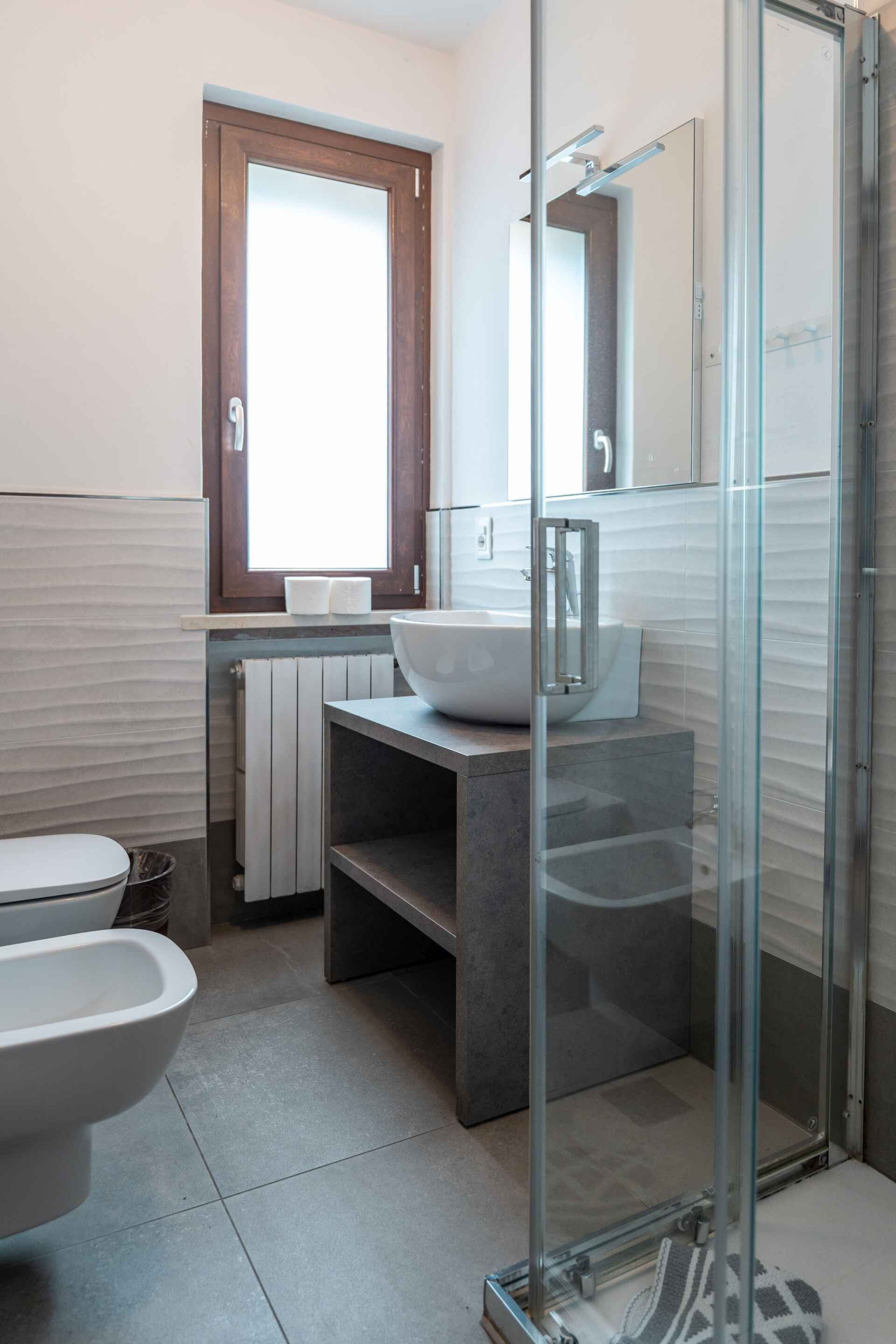 Un baño moderno con ducha de vidrio, lavamanos blanco y retrete.
