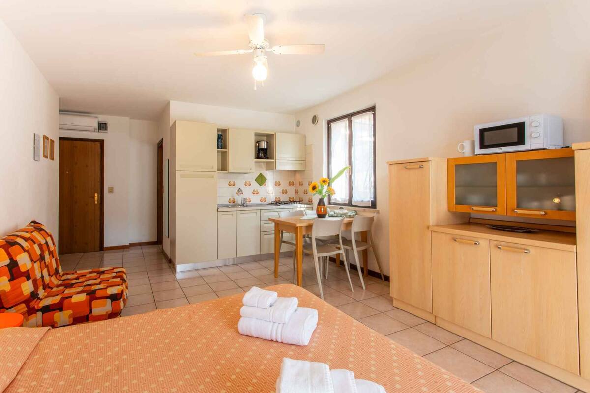 Quarto de hotel compacto com cozinha compacta, espaço para refeições e cama com toalhas.